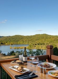 A scenic deck view with a dining setup overlooking a serene lake and green hills.