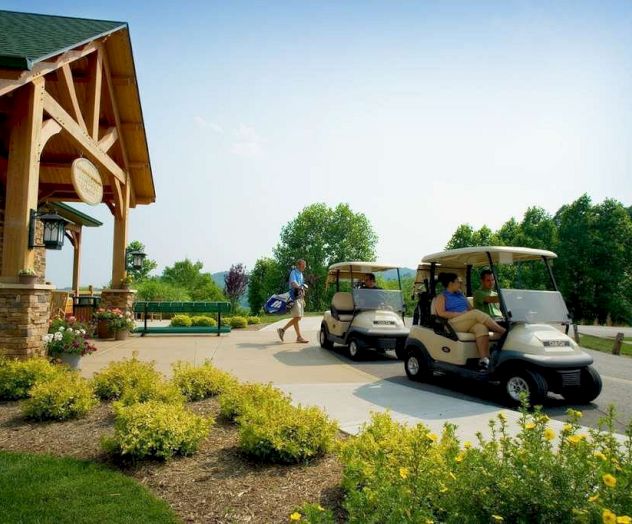 Two golf carts in front of a building with people nearby on a sunny day.
