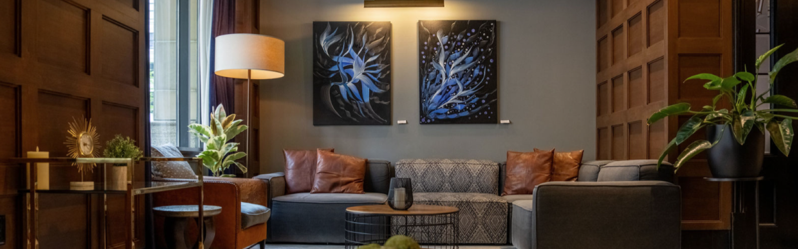 This is a cozy, stylish living room with modern artwork, plants, and comfortable seating options.