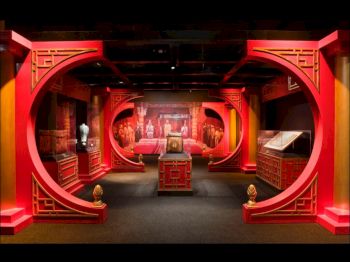 The image shows a richly decorated room with red Chinese-style arches, ornate furniture, and art displays, creating an immersive cultural exhibit.