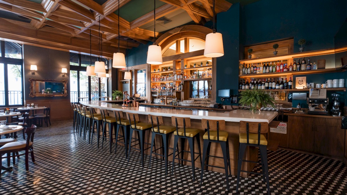 Stylish cafe with bar stools, pendant lights, and checkered floor.