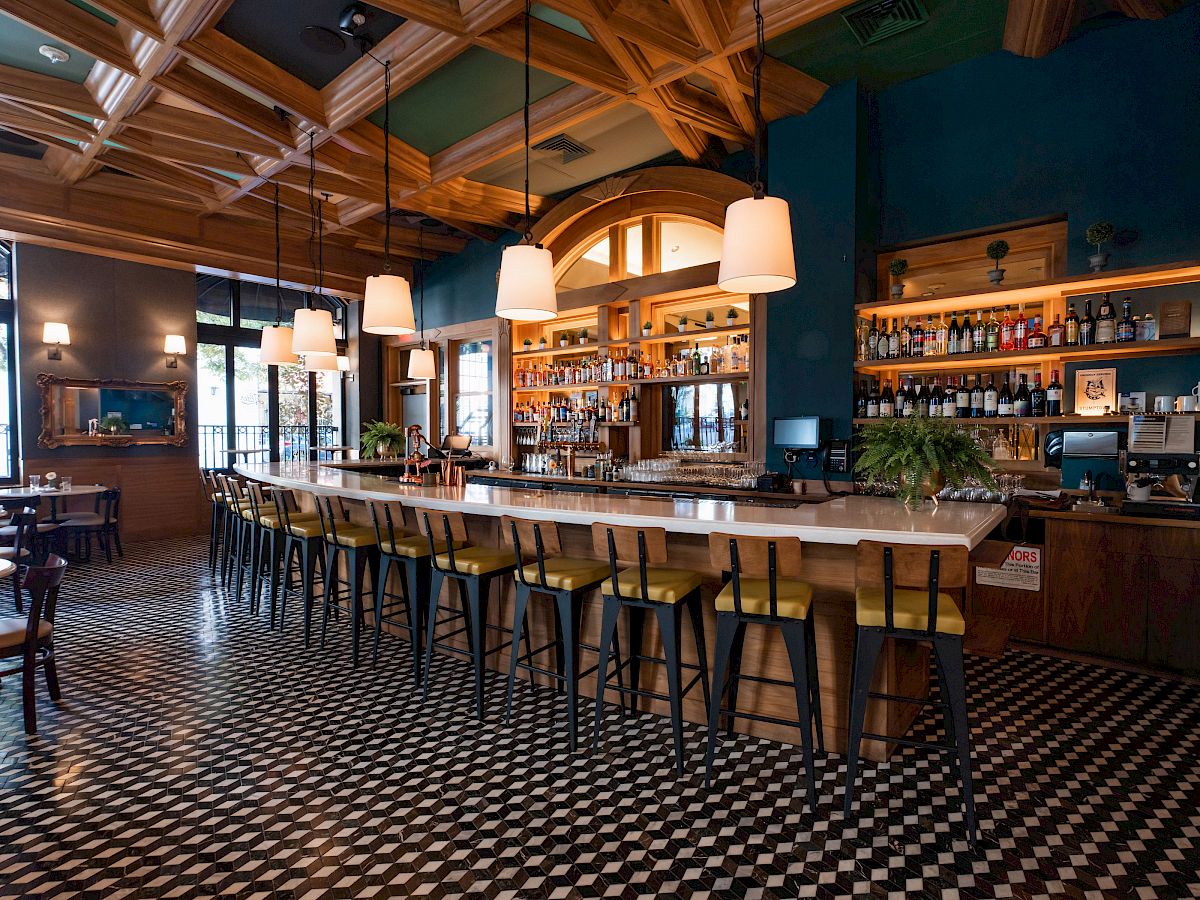 Stylish cafe with bar stools, pendant lights, and checkered floor.