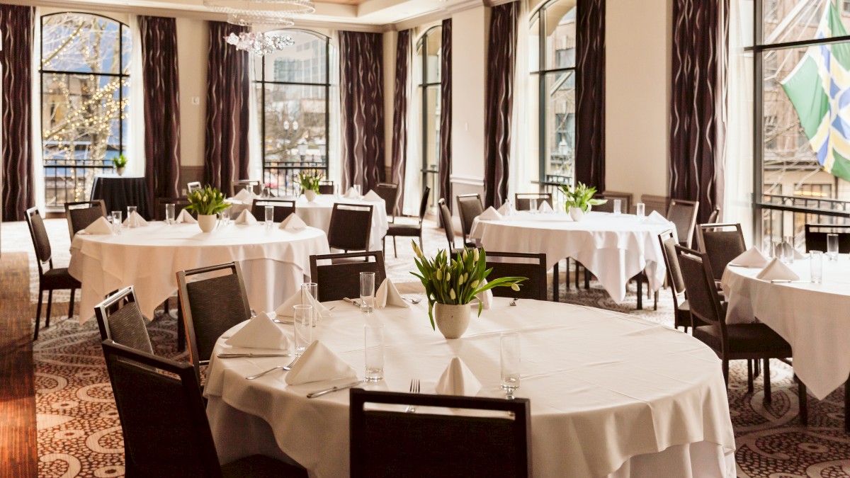 An elegant dining room with white tablecloths and flowers.