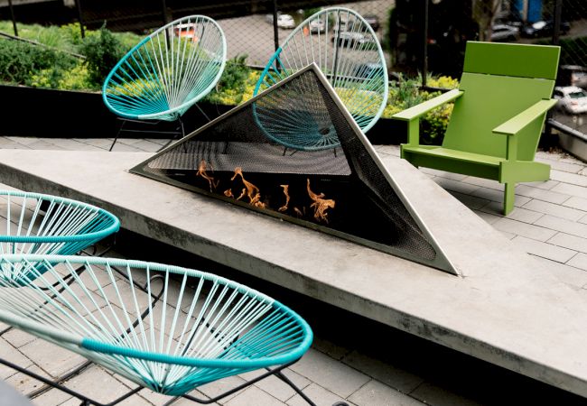 Modern outdoor seating area with stylized chairs and a fire pit centerpiece.