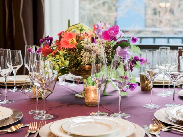 A beautifully set dining table with a floral centerpiece, fine china, silverware, and glasses arranged neatly, ready for a special meal.