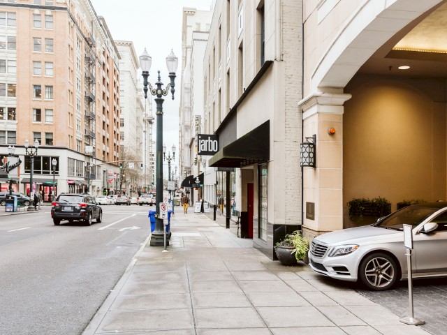 A city street scene with buildings, parked cars, streetlights, and a shop labeled 