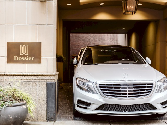 A white Mercedes-Benz is parked in a hotel entrance with a 