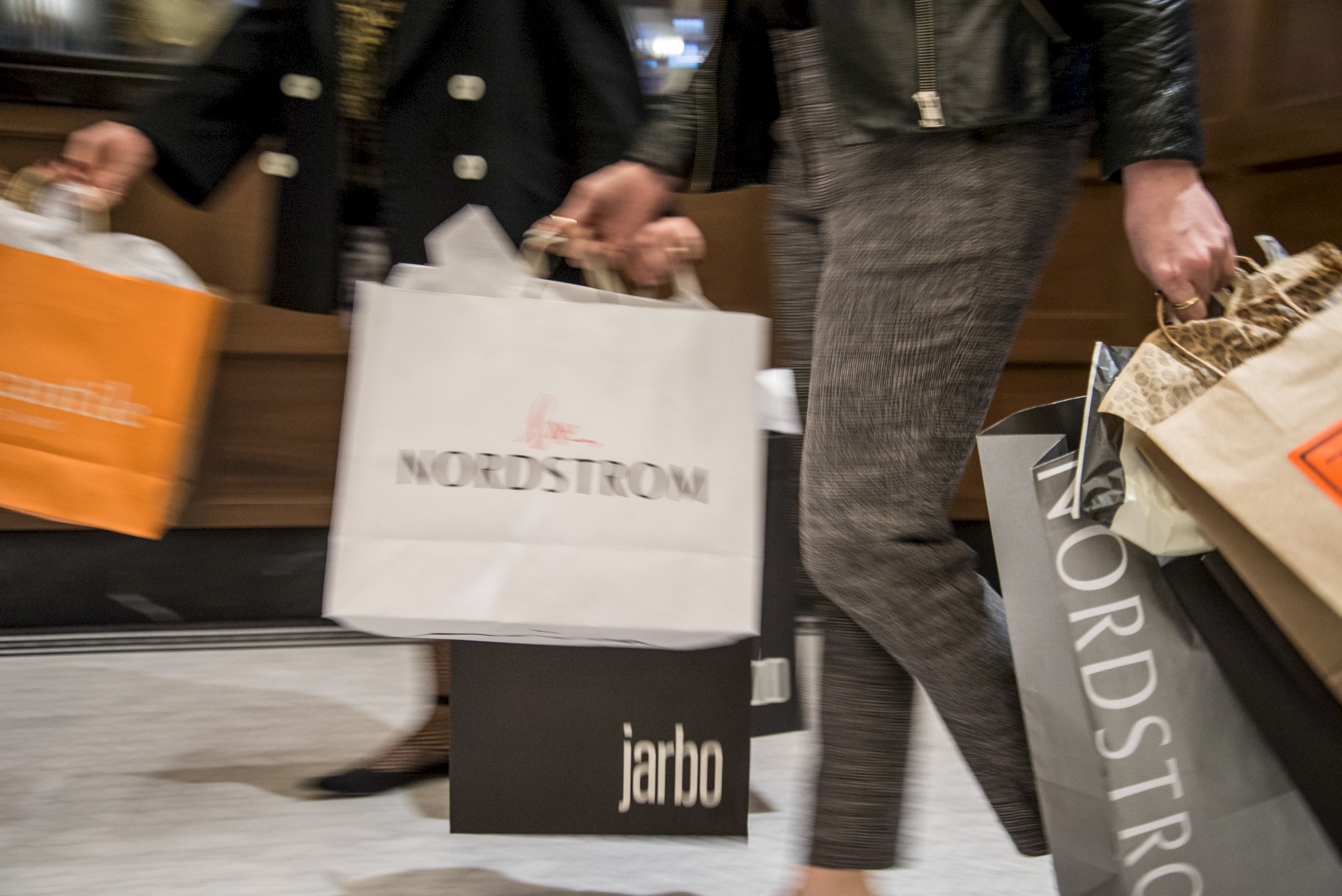 People carrying Nordstrom and other branded shopping bags indoors.