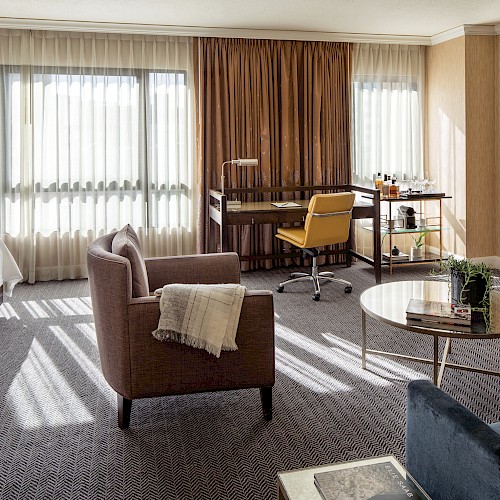 Premium Corner Room - A modern hotel room with a bed, seating area, desk, TV, and beverage cart, featuring a large window with curtains and a cozy atmosphere.