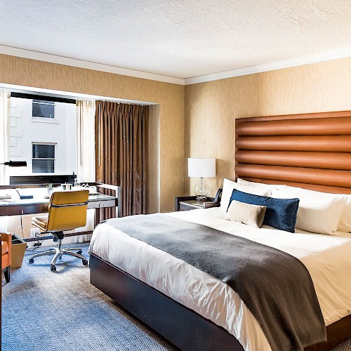 Standard Room - A modern hotel room with a large bed, desk area, chair, lamp, and window with curtains, creating a comfortable and inviting space.