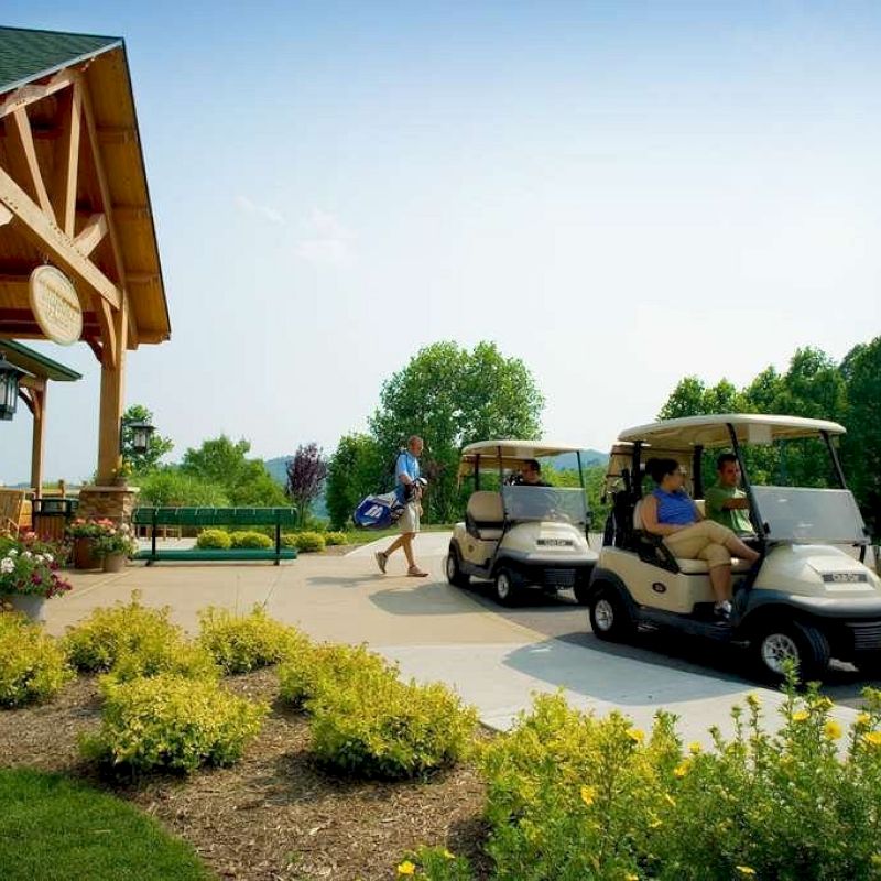 Golf carts parked by a clubhouse with people enjoying a sunny day.