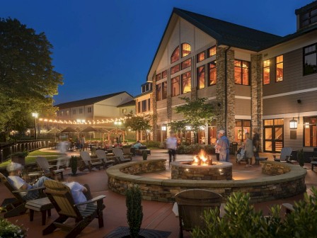 An outdoor patio at dusk with a fire pit, furniture, and people enjoying the evening.