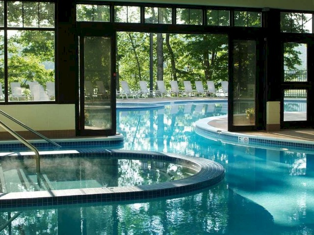 Indoor swimming pool with clear blue water and outdoor view through windows.