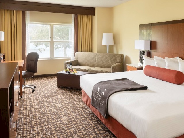 Comfortable hotel room with a bed, sofa, desk, and window view.
